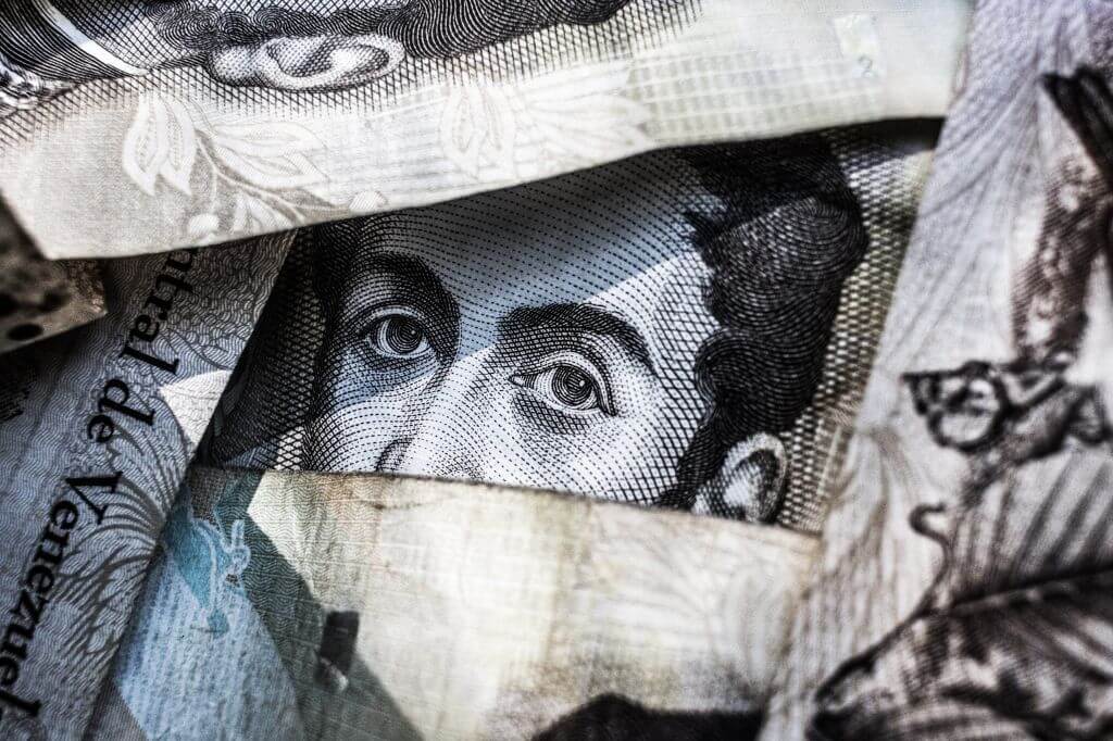 Money notes piled up with the face of a man on the notes peering through