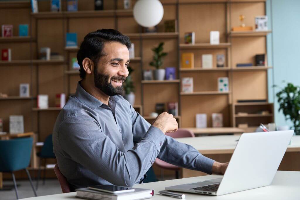 Happy man in office talking to someone on a laptop