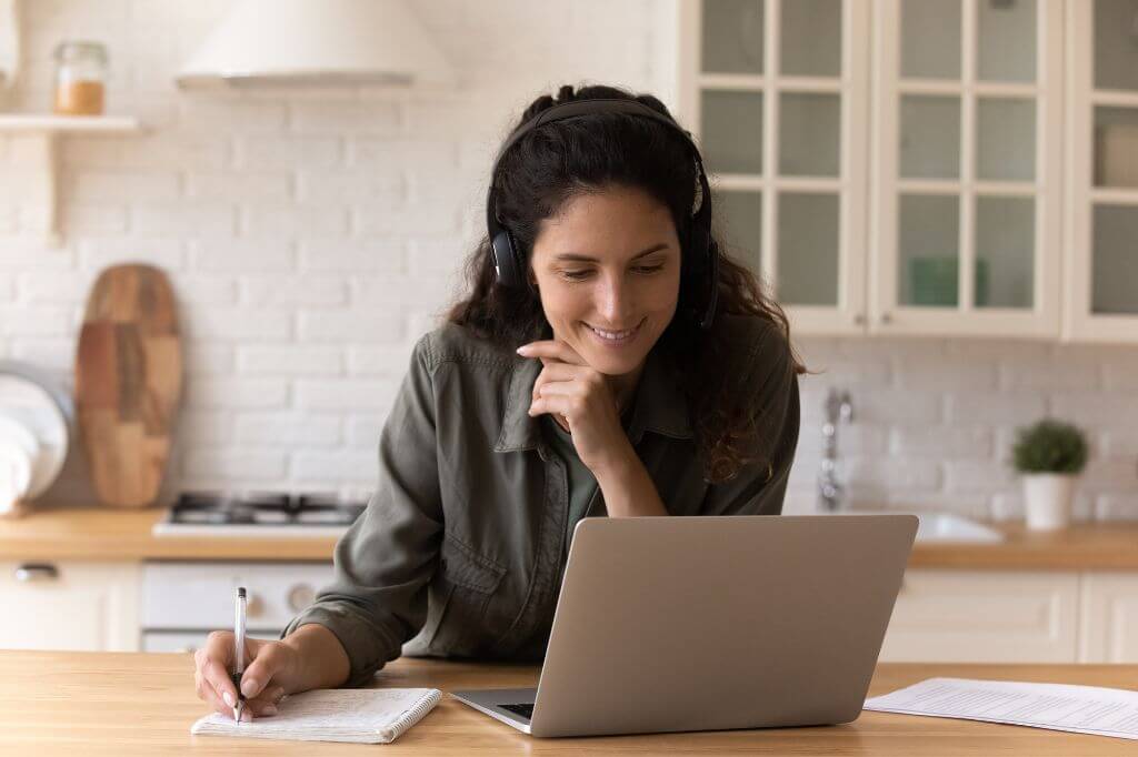 Woman watching a webinar taking notes