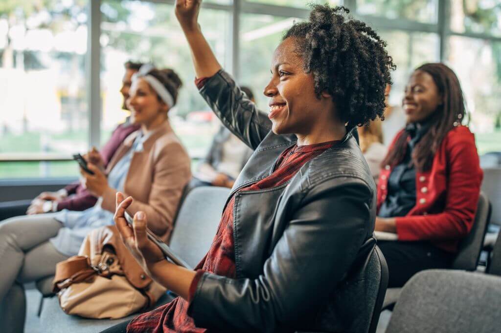 Woman with her hand raised at a conference