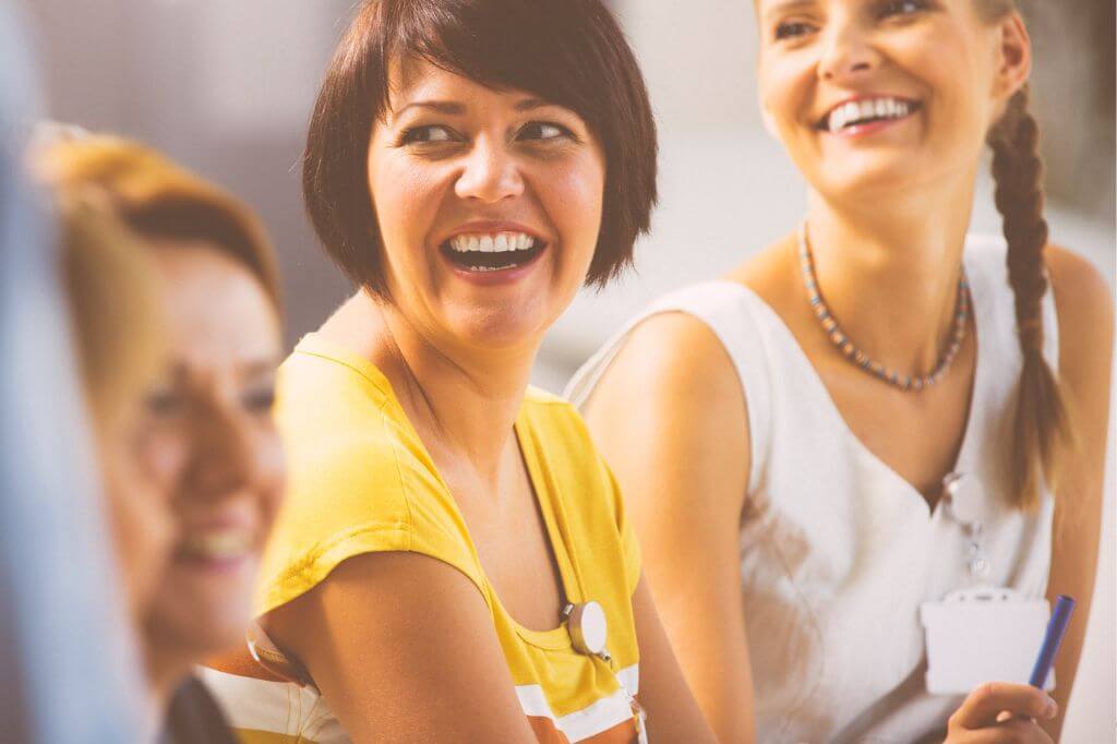 Woman sat together laughing at a conference