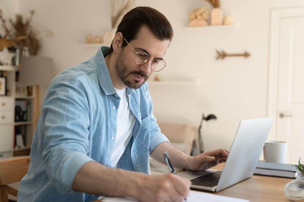 Man taking notes while watching a webinar