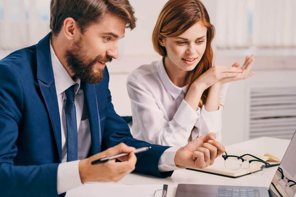 Man and woman in office having a discussion whilst looking at a laptop