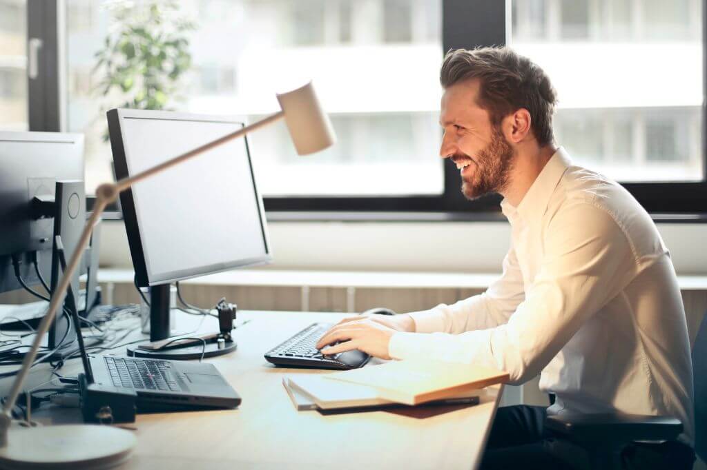 Man in office happy working on laptop