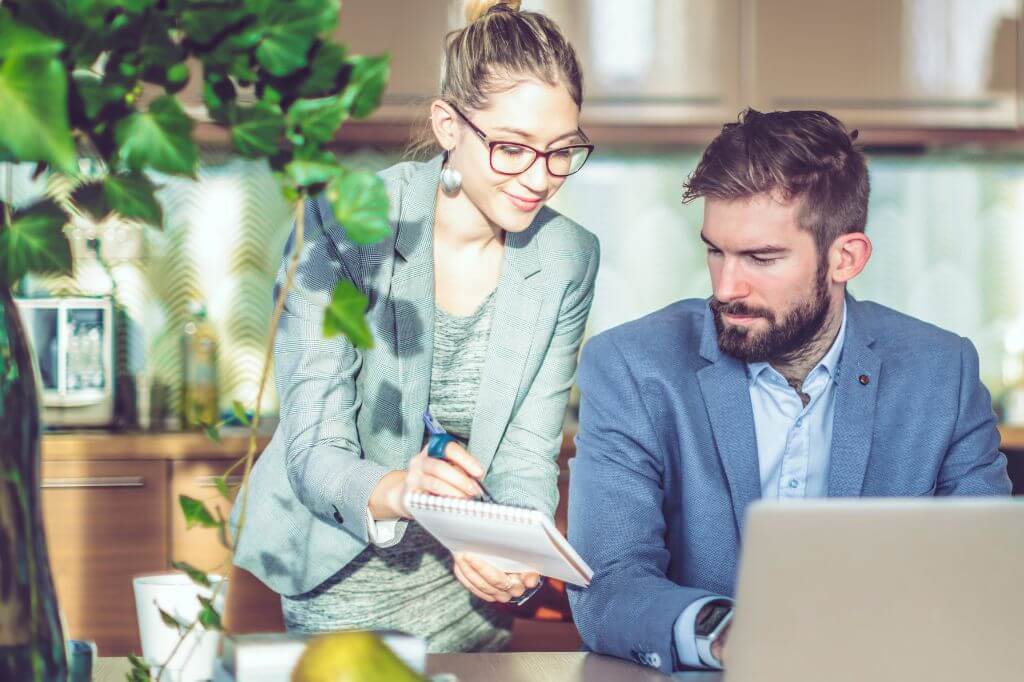 Man and woman in office discussing something on a notepad