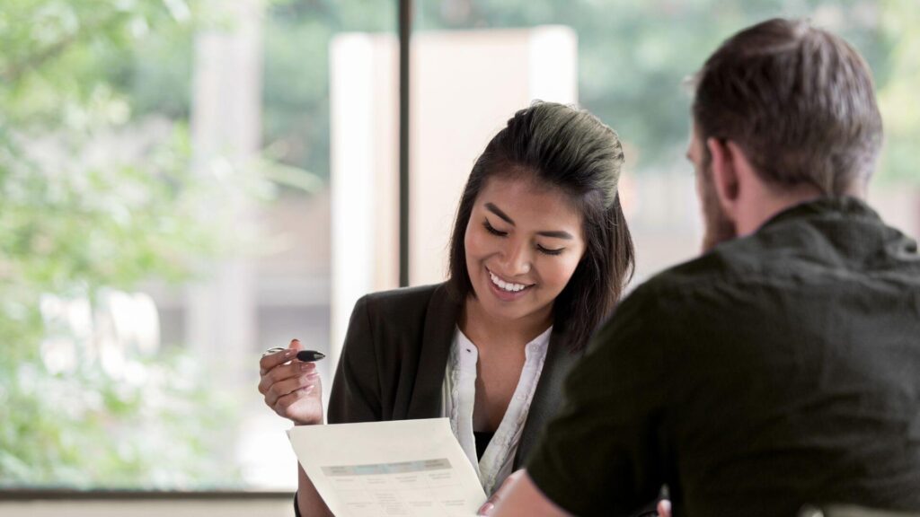 Woman smiling reviewing paperwork of a man